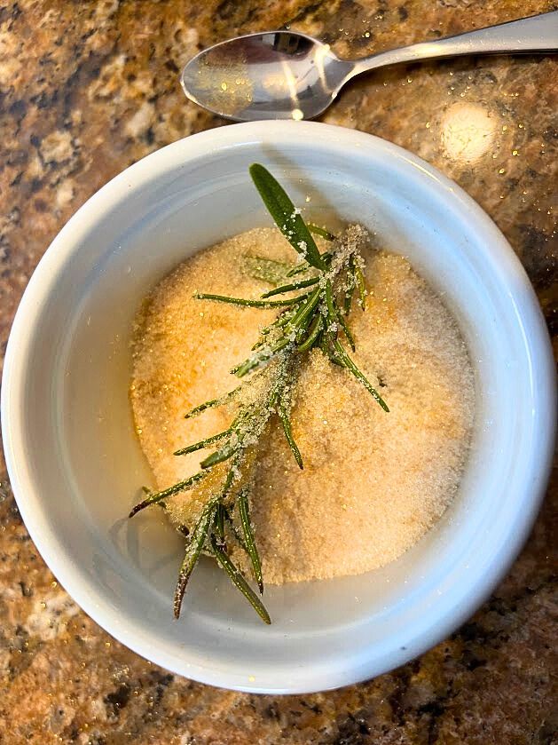 A dusting of sugar and edible gold luster on rosemary for a festive cocktail garnish. 