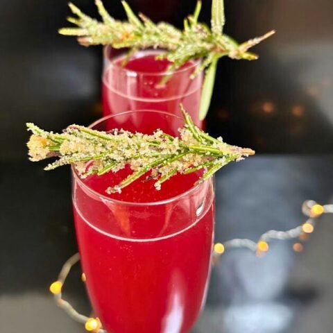 A refreshing holiday cocktail made with gin, pomegranate juice, lemon juice, and prosecco, garnished with frosted rosemary.