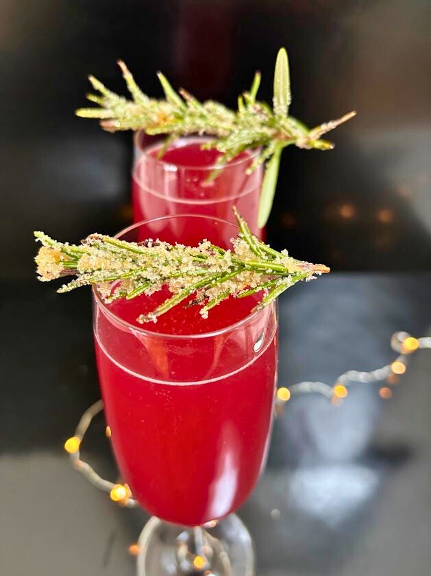 A refreshing holiday cocktail made with gin, pomegranate juice, lemon juice, and prosecco, garnished with frosted rosemary. 