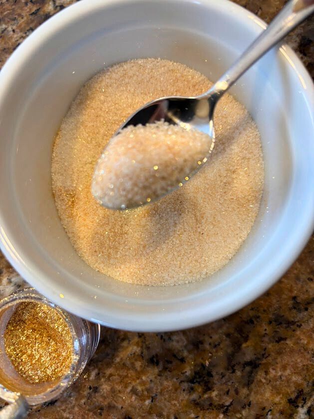 A dusting of sugar and edible gold luster on rosemary for a festive cocktail garnish. 